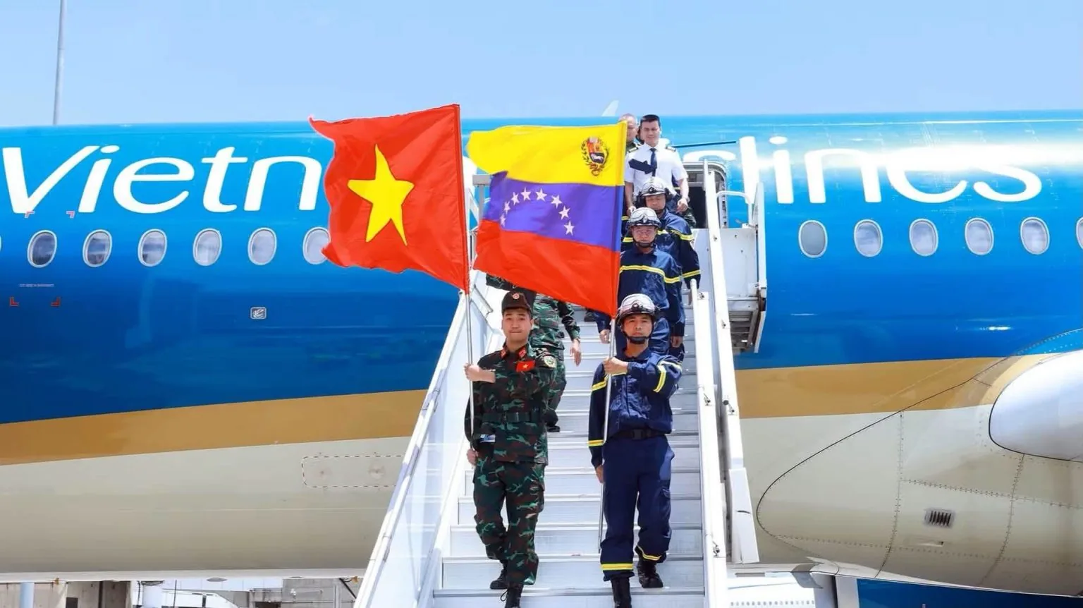 Cán bộ, chiến sĩ lực lượng cứu hộ Việt Nam rời tàu bay của Vietnam Airlines, mang theo cờ Việt Nam và Venezuela.